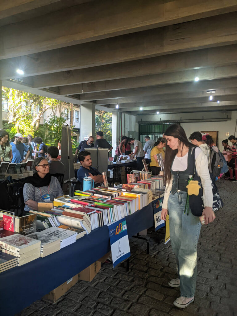 Imagem que uma das visitantes da FLUFF observando os materiais da editora Lamparina.